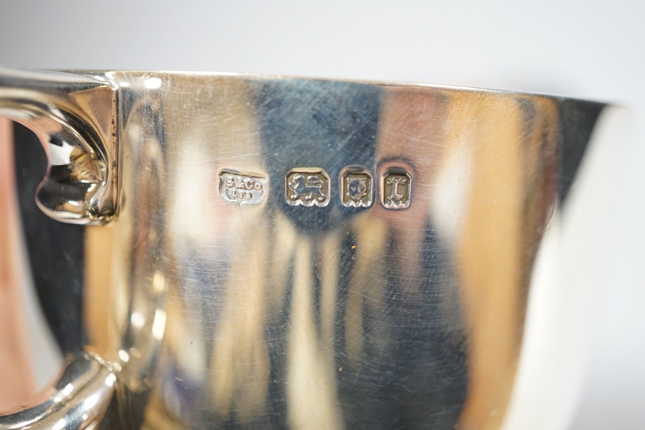 A George V silver cup, with single handle, Searle & Co, London, 1932, height 61mm, together with a pair of late Victorian silver napkin rings, Charles Edwards, London, 1899, 8oz.
